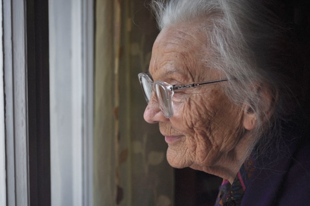 elderly woman looking out a window