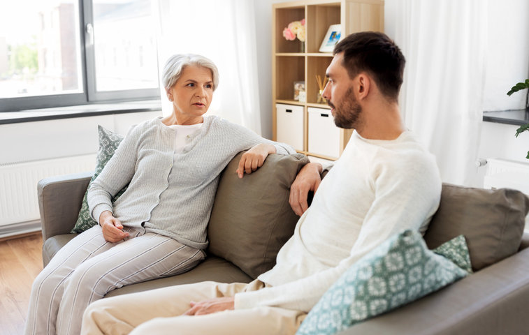 man speaking to his mother on the sofa about care homes